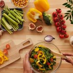 Top view of fresh vegetables and salad preparation on a wooden table, perfect for healthy eating concepts.