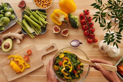 Top view of fresh vegetables and salad preparation on a wooden table, perfect for healthy eating concepts.